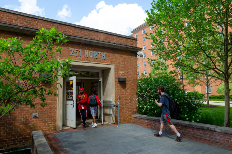 Students walk through the entrance of the brick 251 North dining hall on a sunny day.