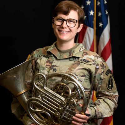 Kat holding horn in army uniform