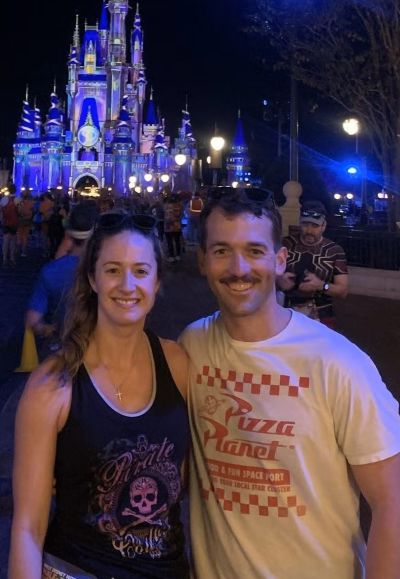 a happy couple standing in front of Disney castle 