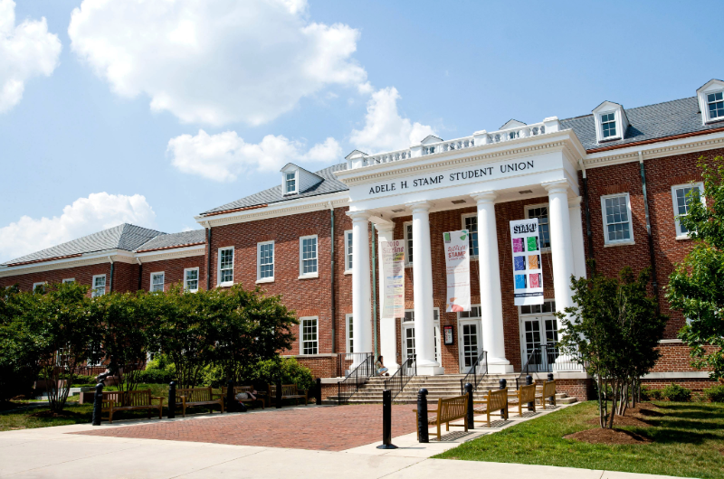 The brick exterior and white columns of the Adele H. Stamp Student Union under a blue sky.