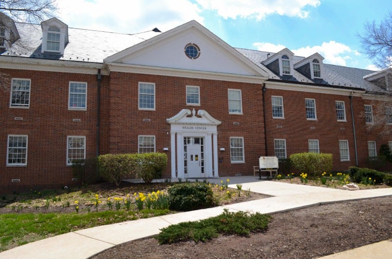 Exterior of the red brick University Health Center with yellow flowers in front.