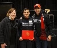 young man holding award smiling in group photo
