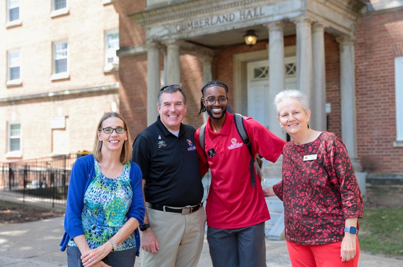 A group of smiling DSA staff members during move-in outside of Cumberland Hall.