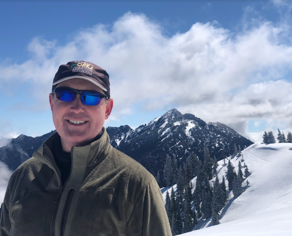 Man smiling in front of snowy mountains