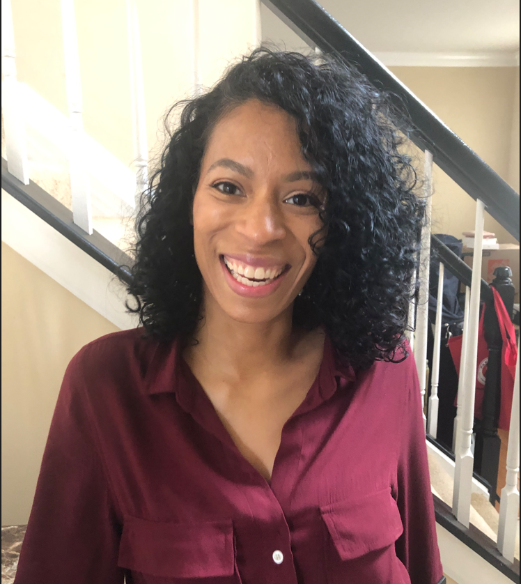 Woman smiling and wearing a blouse in front of a set of stairs