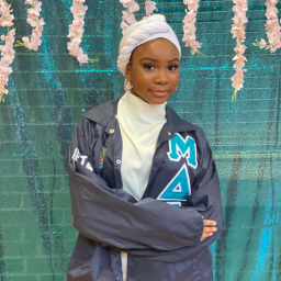 Woman wearing a letterman jacket with her arms crossed