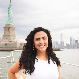Woman smiling on a boat in front of the Statue of Liberty