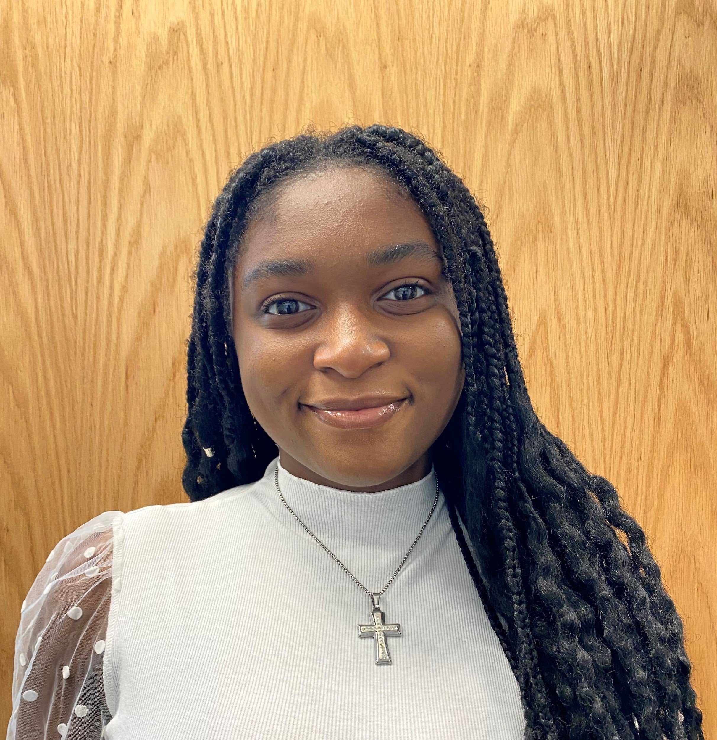 Woman with a soft smile wearing a cross necklace