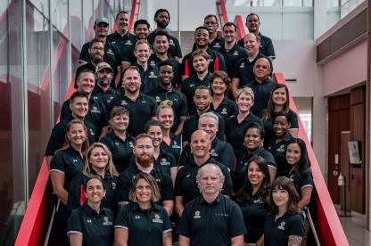 RecWell staff in black polos take a photo on a staircase
