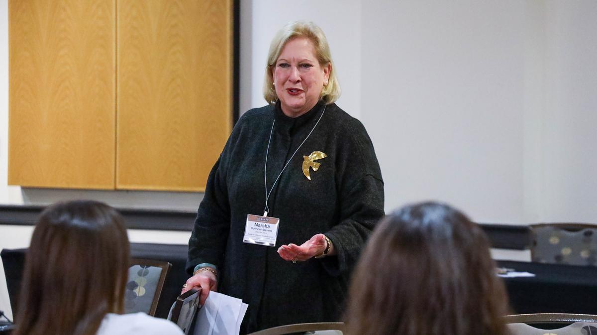 A staff member with a microphone talks to an audience of other staff