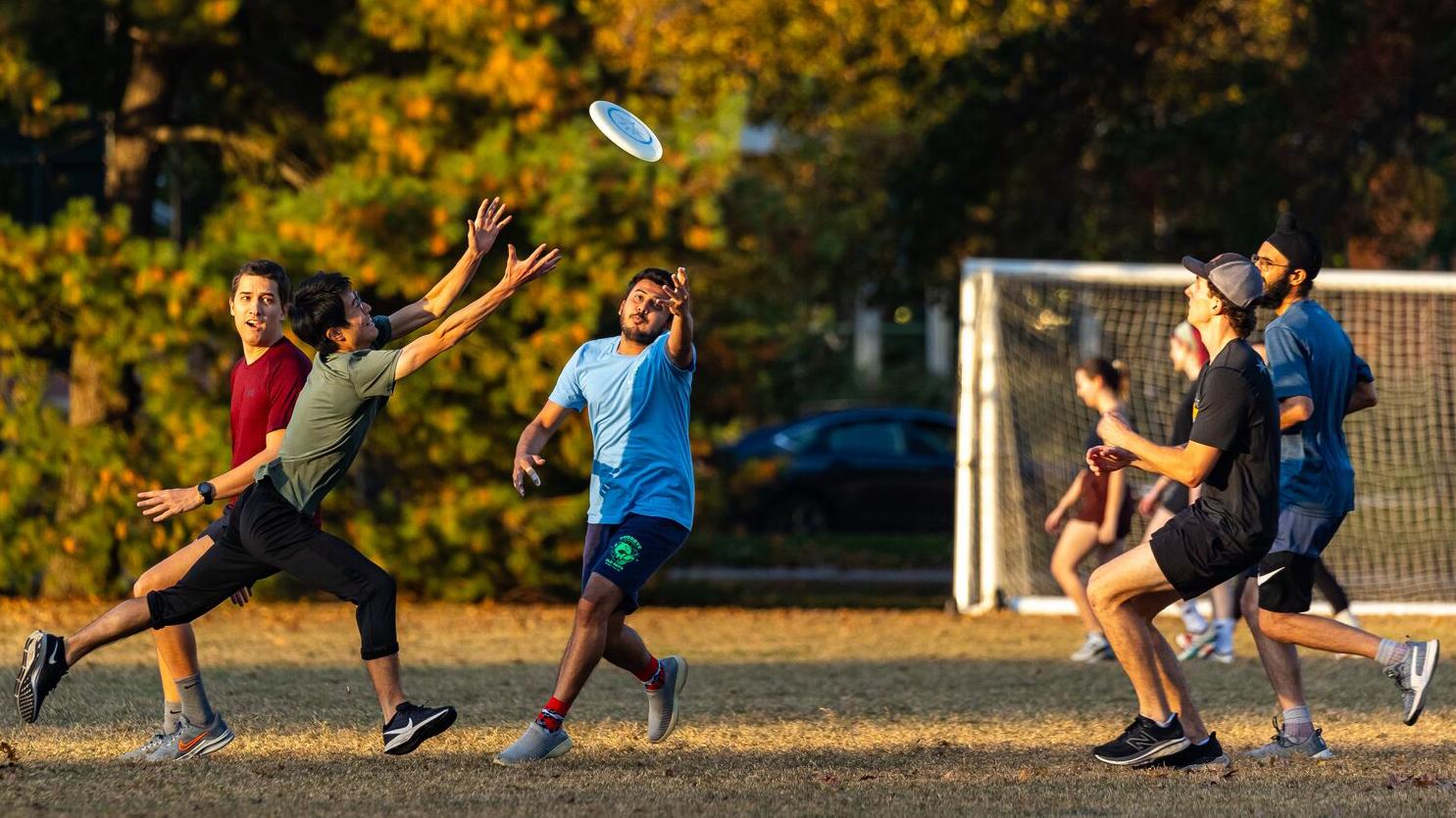 A group of students attempt to catch a frisbee while playing outdoors