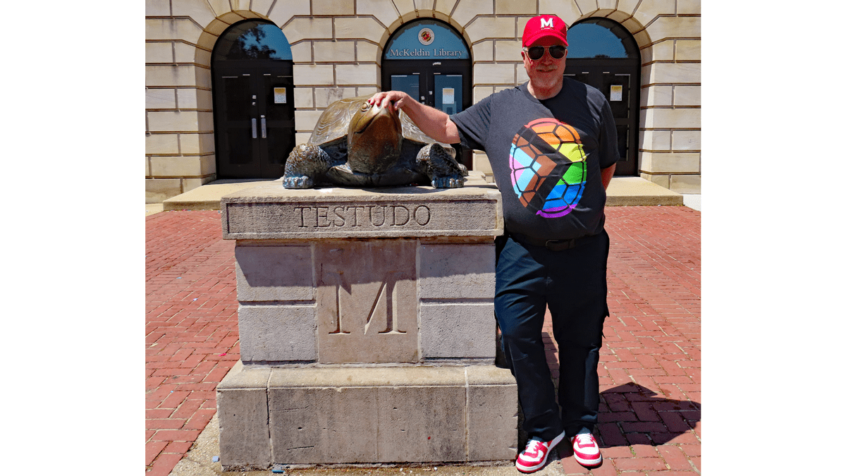 Rocky Lopes standing next to Testudo statue. 