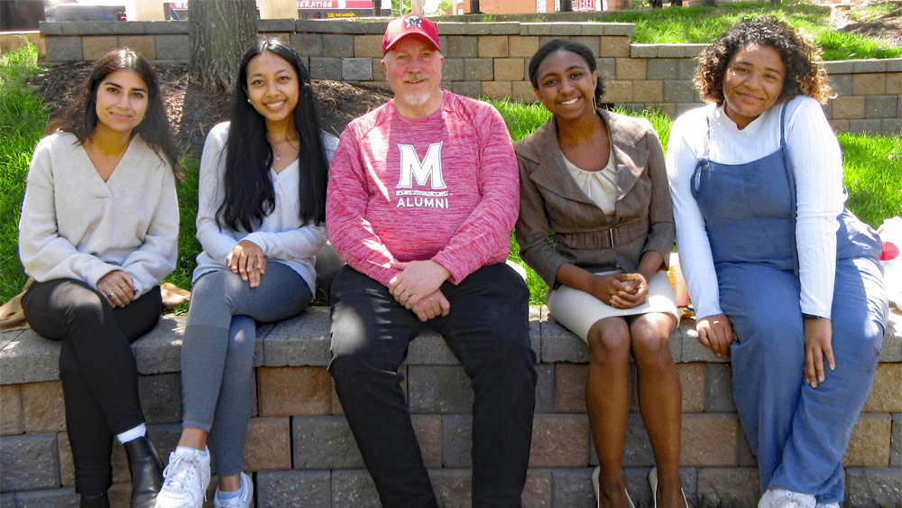 Rocky Lopes sitting next to students.