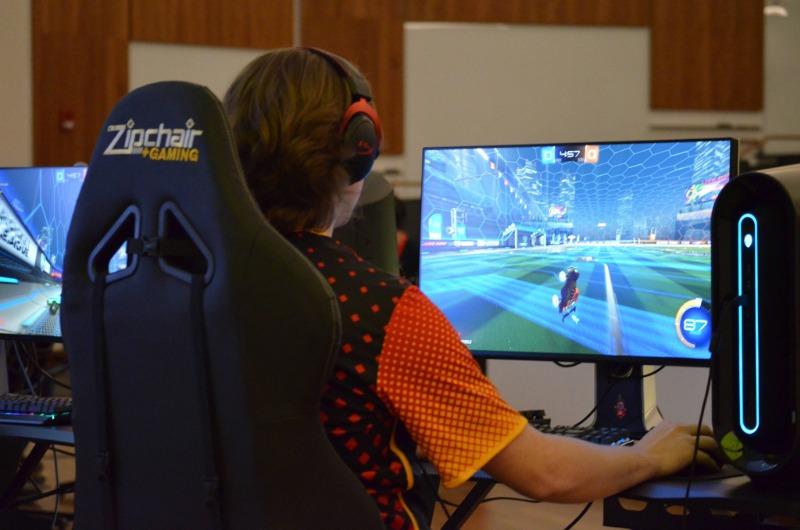 A student wearing a headset competes in a video game at an esports station.