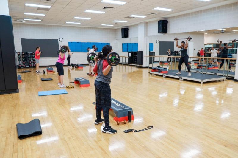 Students lift barbells during a group fitness class in Eppley.