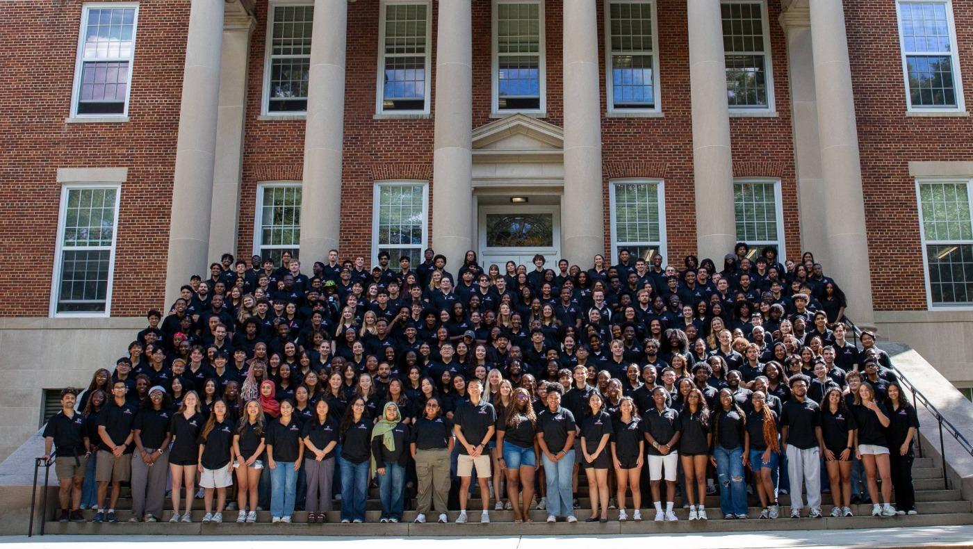Large group of resident assistants in matching black shirts posing on the steps of Francis Scott Key Hall.