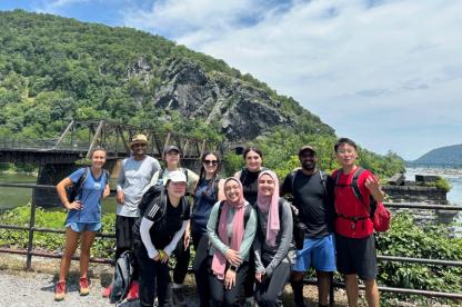 A diverse group of students poses for a photo during a mountain hiking trip.